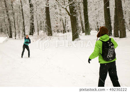 Beautiful happy couple throwing snowballs and having fun in winter park 49230222