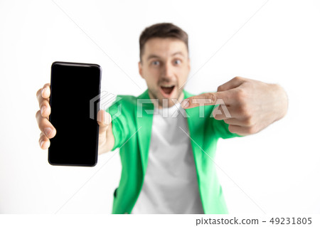 Young handsome man showing smartphone screen and signing OK isolated on gray background Young handsome man showing smartphone screen and signing OK isolated on gray background 49231805