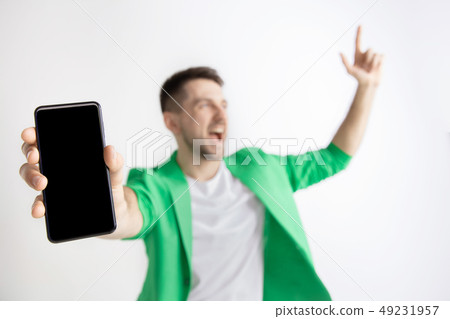 Young handsome man showing smartphone screen and signing OK isolated on gray background Young handsome man showing smartphone screen and signing OK isolated on gray background 49231957