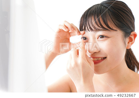 Woman doing contact lens Woman doing contact lens 49232667