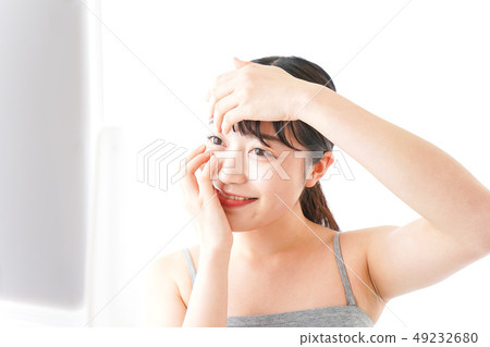 Woman doing contact lens Woman doing contact lens 49232680