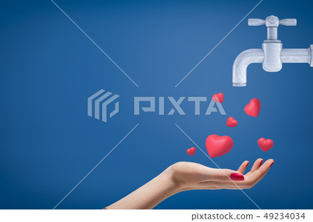 Side crop close-up of woman's hand facing up and catching cute red hearts coming from grey tap on 49234034