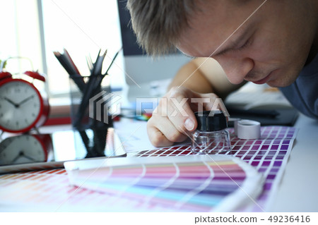 Male serviceman hold in hand magnifying glass making colour test Male serviceman hold in hand magnifying glass making colour test 49236416