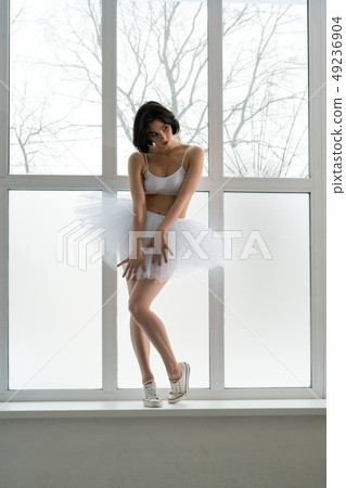 Young girl in tutu and sneakers on window sill 49236904