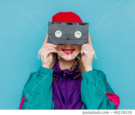 woman in red hat, sunglasses and suit of 90s with VHS cassette woman in red hat, sunglasses and suit of 90s with VHS cassette 49239529