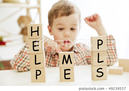 Wooden cubes with words HELP ME PLS in hands of little boy 49239557