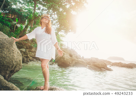 a woman in sun glasess on a rock looking into the a woman in sun glasess on a rock looking into the 49243233