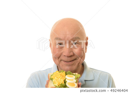 Senior eating egg dish on bread Senior eating egg dish on bread 49246404