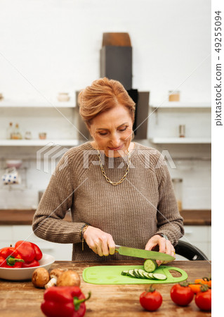 Beaming good-looking in sweater being at home alone and preparing meal Beaming good-looking in sweater being at home alone and preparing meal 49255094