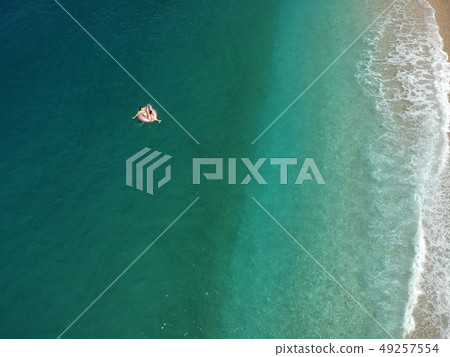 Aerial view young woman on giant inflated flamingo float in turquois water of Ionian Sea Albania 49257554