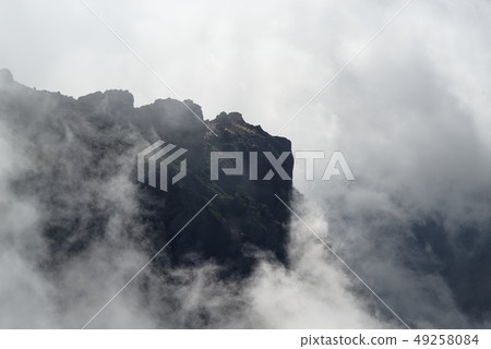 Dark rock formation inside of raised clouds 49258084