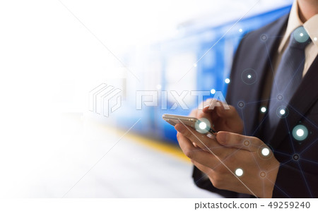 一位商人正在火車站使用智慧型手機。 49259240