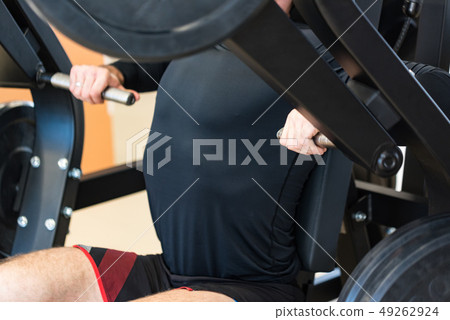 Athlete does chest press exercises on gym machine close view Athlete does chest press exercises on gym machine close view 49262924