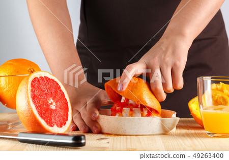 girl preparing fresh citrus juice. gray background girl preparing fresh citrus juice. gray background 49263400