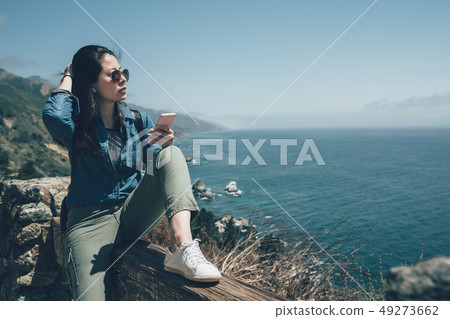 woman hiker use smart phone in Big Sur Coastline woman hiker use smart phone in Big Sur Coastline 49273662