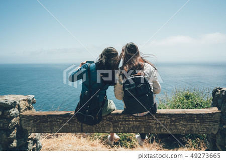 backpackers sitting on wooden bench chair backpackers sitting on wooden bench chair 49273665