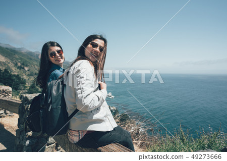 friends sitting on wooden railing cliff friends sitting on wooden railing cliff 49273666