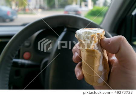 the driver holds the ice cream while driving a car 49273722