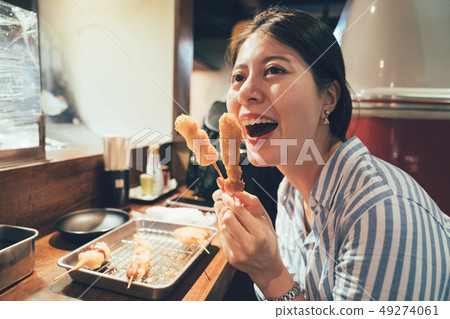 girl try japanese dish deep-fried skewered meat 49274061