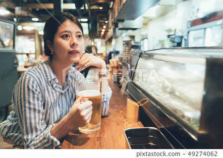 woman holding beer sitting at bar counter 49274062