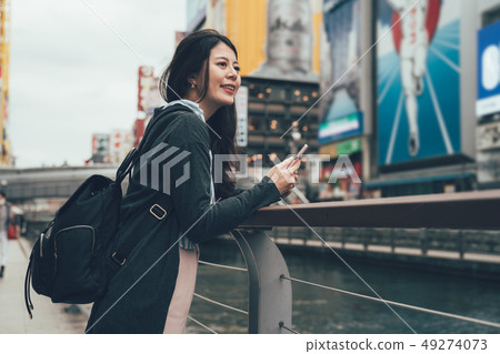 girl holding mobile phone leaning against bridge 49274073