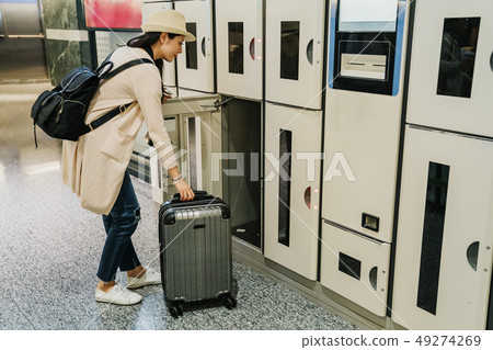 female backpacker putting luggage in coin locker female backpacker putting luggage in coin locker 49274269