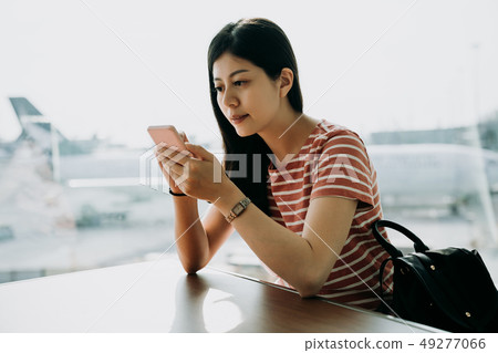 traveler using phone at airport sitting at table 49277066