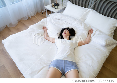 sad girl lying in middle white bed top view. sad girl lying in middle white bed top view. 49277349