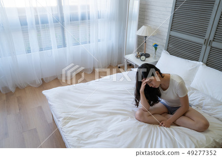 lonely girl sitting in bed alone in bedroom lonely girl sitting in bed alone in bedroom 49277352