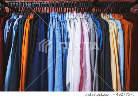 Multi colored clothing hanging on hangers 49277573