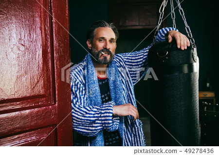 A Brutal Looking Man With a Beard Smokes a Cigarette After Taking a Shower. 49278436
