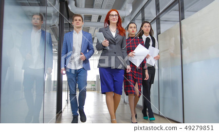 A successful business people walking through the corridor holding papers A successful business people walking through the corridor holding papers 49279851