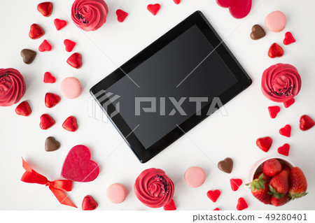 close up of tablet pc and sweets on valentines day close up of tablet pc and sweets on valentines day 49280401