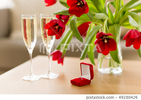 diamond ring, champagne and flowers on table diamond ring, champagne and flowers on table 49280426