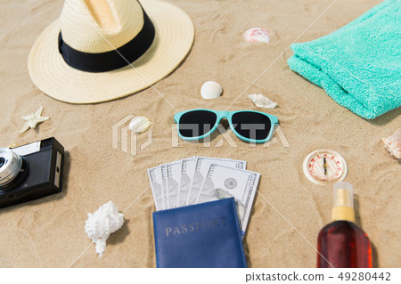 money in passport, shades and hat on beach sand money in passport, shades and hat on beach sand 49280442