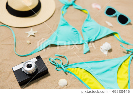 bikini, hat, camera and sunglasses on beach sand bikini, hat, camera and sunglasses on beach sand 49280446
