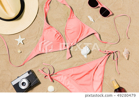 bikini, hat, camera and sunglasses on beach sand 49280479
