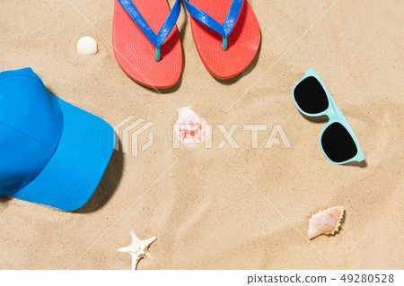 cap, flip flops, shades and on shells beach sand 49280528