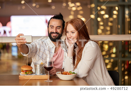 couple taking selfie by smartphone at restaurant 49280712
