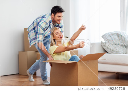 happy couple having fun with box at new home happy couple having fun with box at new home 49280726