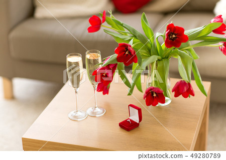 diamond ring, champagne and flowers on table diamond ring, champagne and flowers on table 49280789