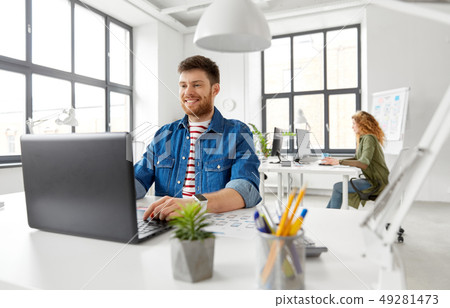smiling creative man with laptop working at office smiling creative man with laptop working at office 49281473