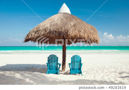 two sun chairs under palapa on tropical beach 49281619