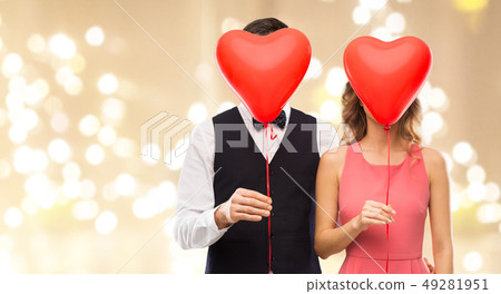 couple hiding behind red heart shaped balloons 49281951