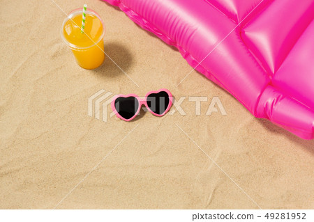 sunglasses, juice and pool mattress on beach sand sunglasses, juice and pool mattress on beach sand 49281952