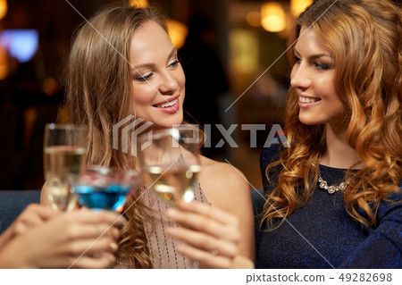 happy women clinking glasses at night club happy women clinking glasses at night club 49282698