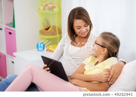 happy mother and daughter with tablet pc at home 49282941