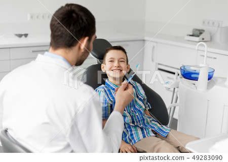 dentist giving toothbrush to kid patient at clinic dentist giving toothbrush to kid patient at clinic 49283090