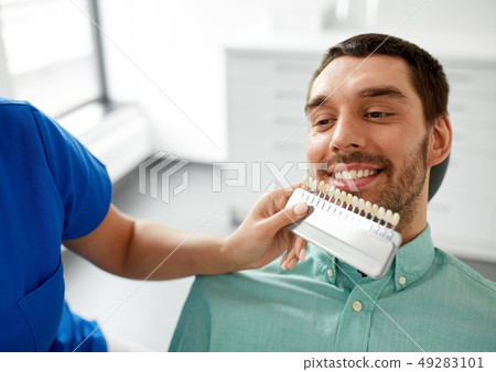 dentist choosing tooth color for patient at clinic 49283101