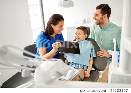 dentist showing tablet pc to kid at dental clinic 49283107